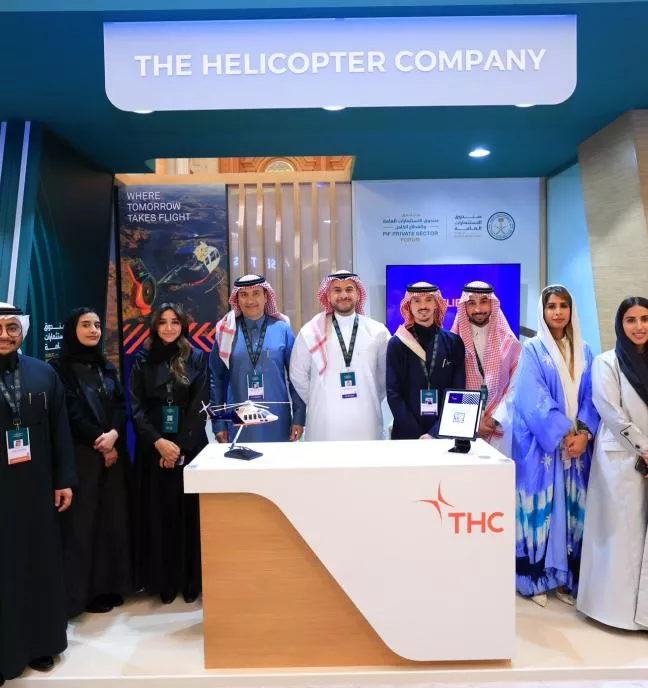 People standing in a group at a company booth, dressed in business attire.